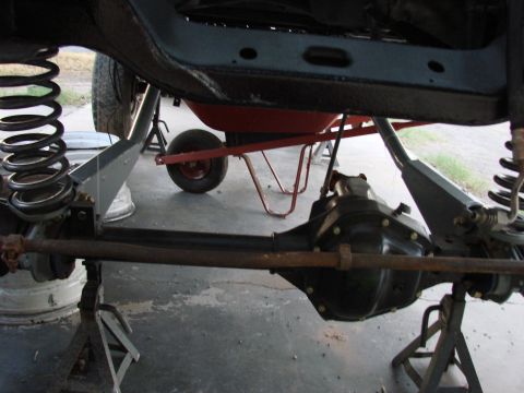 1979 Ford Bronco - Vehicle suspension and differential assembly shown with a wheelbarrow nearby.