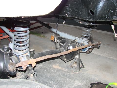1979 Ford Bronco - The front suspension and axle assembly of a vehicle are visible, supported by jack stands for maintenance.