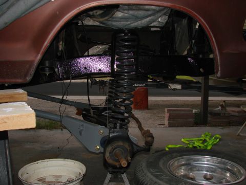 1979 Ford Bronco - Close-up view of the suspension and brake system of a red vehicle, likely undergoing maintenance or repair.