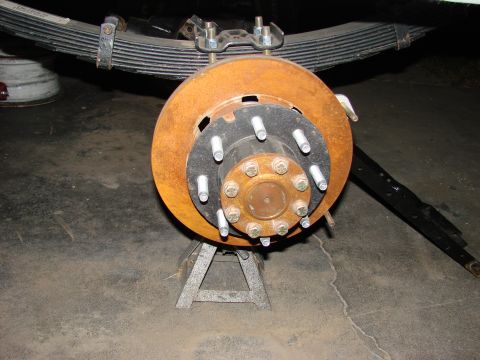 1979 Ford Bronco - Close-up of a heavily rusted brake rotor and hub assembly, resting on jack stands.