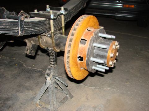 1979 Ford Bronco - The rear axle assembly of a vehicle is shown, supported by jack stands, with a focus on the brake rotor and suspension components.