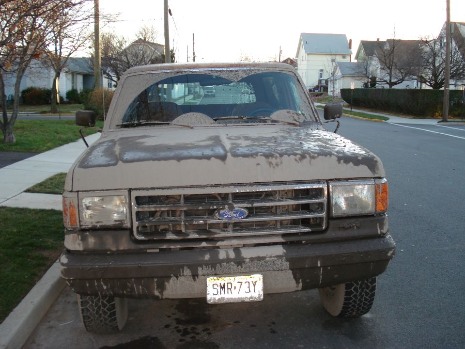 Front view of a mud-covered 1990 Ford Bronco with a license plate SMR-73Y