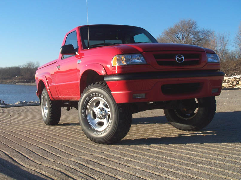 Red 2001 Mazda B3000 pickup truck parked on a ramp near water