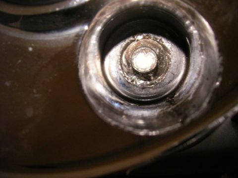 1979 Ford Bronco - Close-up view of a spark plug well, showing a bolt and accumulated debris.