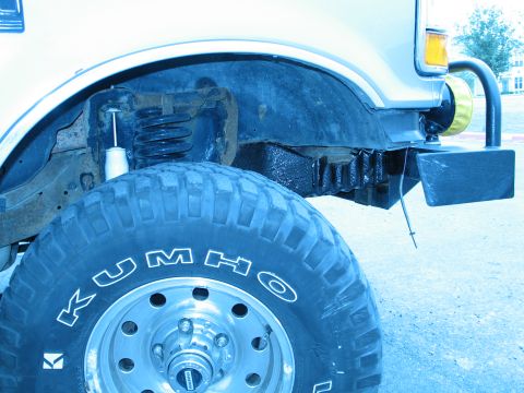 1995 Ford Bronco - Close-up of the front wheel well and suspension of a Ford Bronco, showing off its off-road tires and bumper.