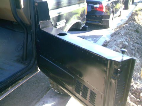 1989 Ford Bronco - The open half door reveals the interior of a 1989 Ford Bronco, with another vehicle visible in the background.