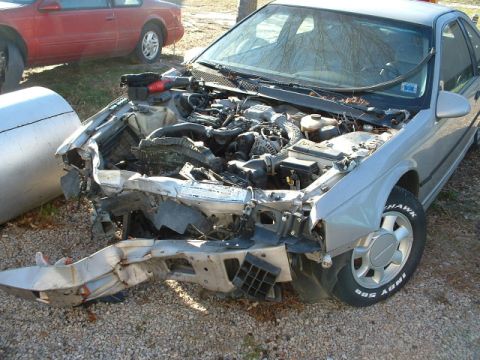 1989 Ford Thunderbird - Damaged 1989 Ford Thunderbird with its engine compartment visible, parked next to another car.