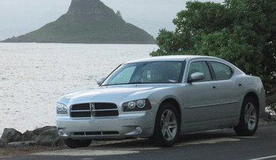 2001 Ford Crown Victoria - A silver Dodge Charger is parked near the water with a distinctive mountain in the background.