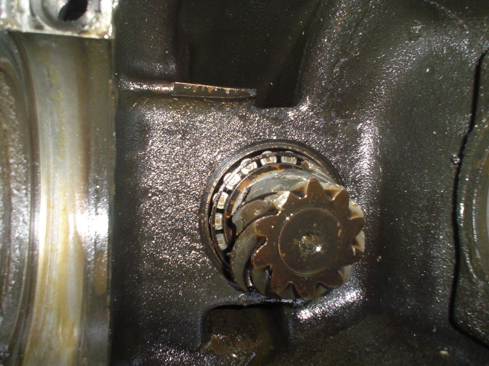 Close-up of a worn differential gear and bearing in greasy housing