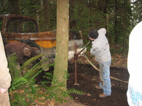 1990 Ford Bronco - A severely damaged truck is being winched out of a wooded area with a jack.