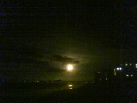 1989 Ford Bronco - A nighttime scene captures the moon and clouds over a body of water, with lights from buildings visible in the distance.