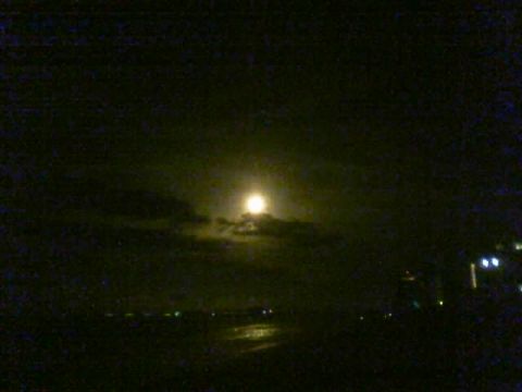 1989 Ford Bronco - Full moon visible through clouds at night, with lights on the horizon.