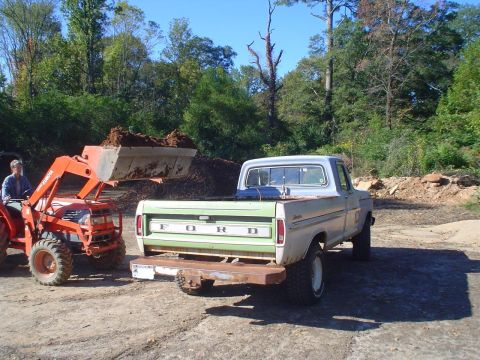 1967 Ford F-250 - A Ford pickup truck is parked next to a tractor loading dirt.