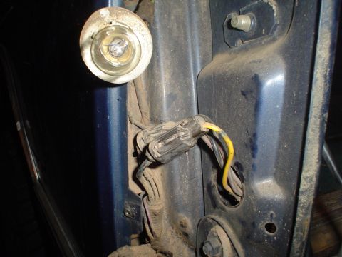 1984 Ford Bronco - Close-up of a dusty, disconnected tail light wiring harness and bulb socket on a blue vehicle.