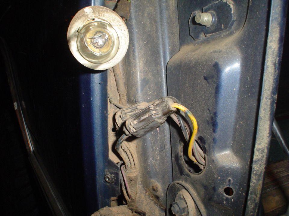 Blue vehicle's rear tail light wiring and bulb socket, dusty and disconnected