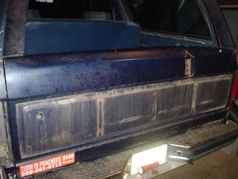 1984 Ford Bronco - The rear tailgate panel of a 1984 Ford Bronco, a 'Turn in Poachers' sticker and visible wear.