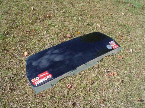 1984 Ford Bronco - A vehicle's tailgate glass, adorned with performance part stickers, rests on a grassy surface.