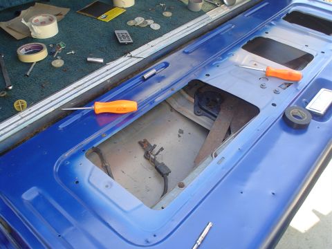 1984 Ford Bronco - Interior of a blue tailgate showing repair work in progress with tools and tape laid out.