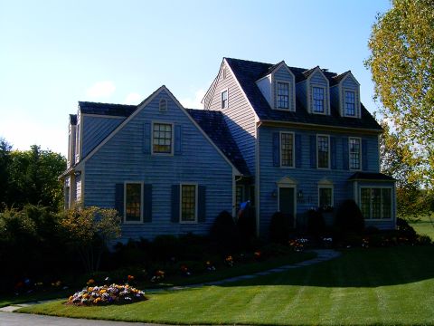 1996 Mercury Grand Marquis - A large blue house with shutters and a manicured lawn is shown on a sunny day.