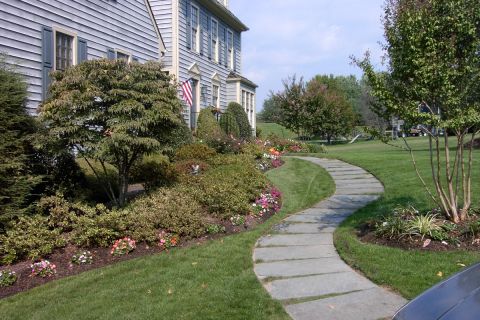 1996 Mercury Grand Marquis - A well-maintained house exterior features a winding stone path through lush landscaping under a clear sky.