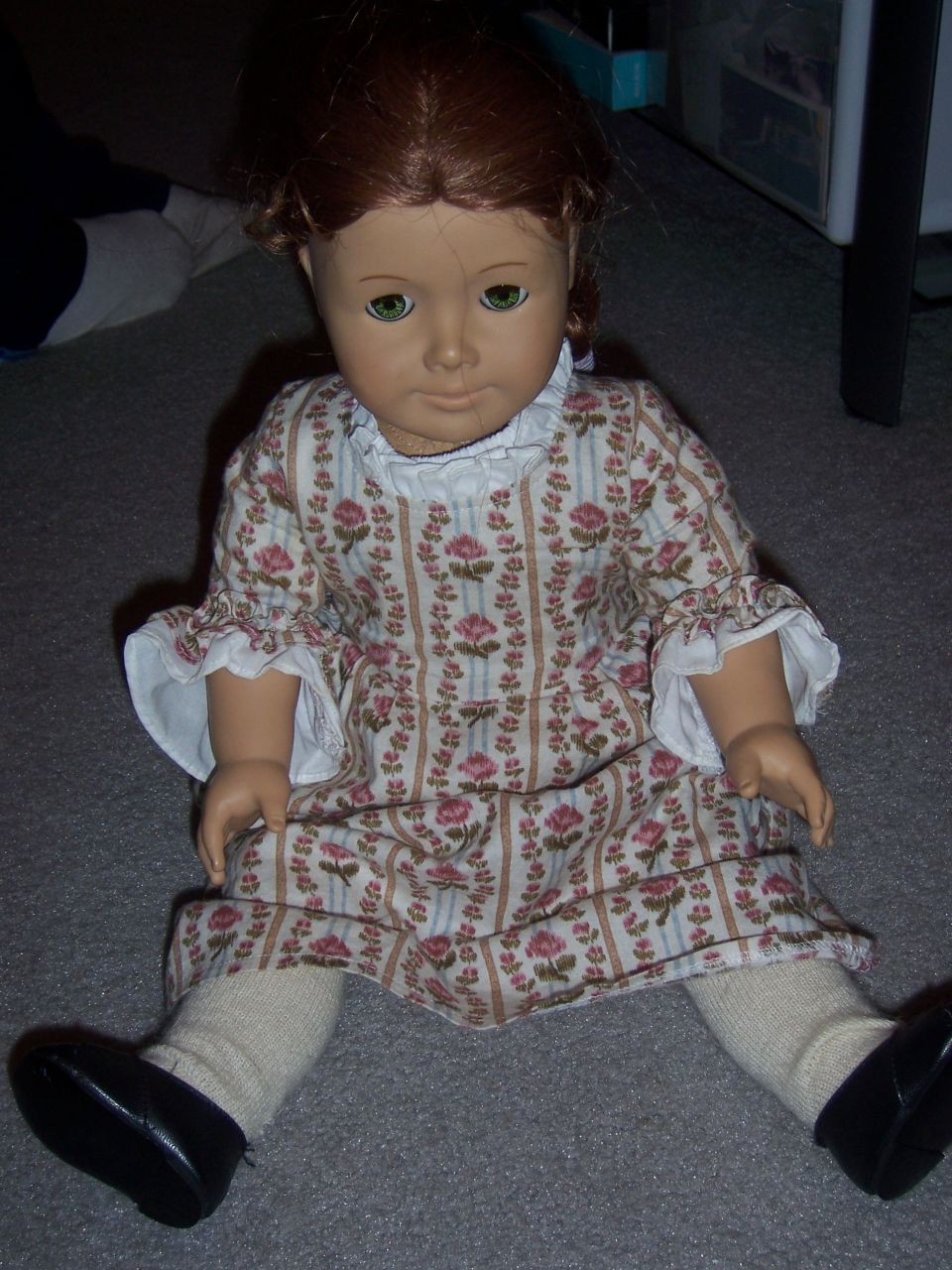 Doll in a floral dress sitting on the floor