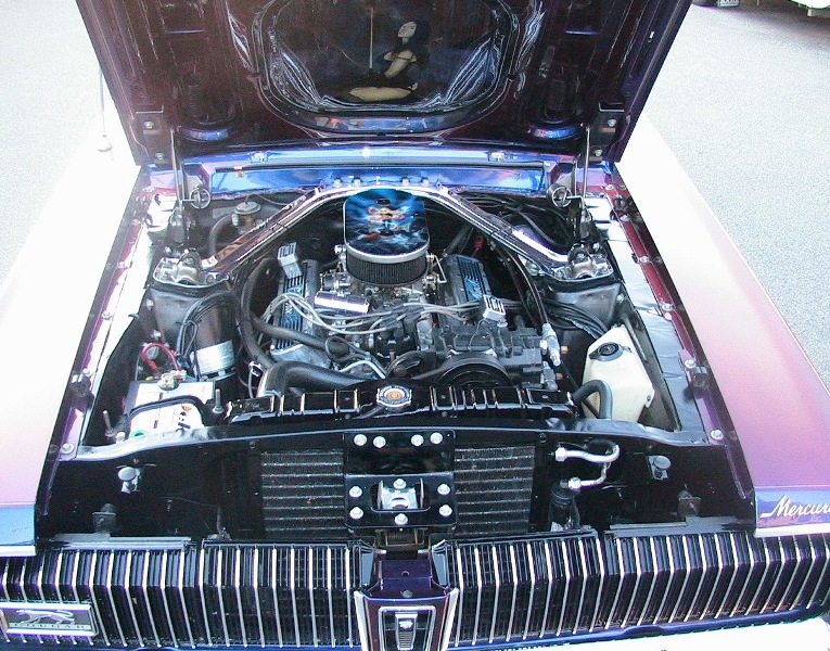Engine bay of blue Mercury with chrome V8 and airbrushed hood art