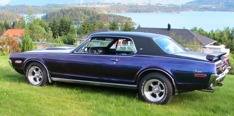 1968 Mercury Cougar - A 1968 Mercury Cougar with a custom purple paint job and a spoiler sits on a lawn overlooking a body of water.