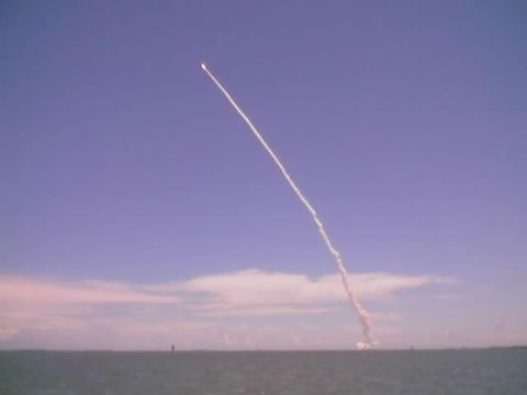 1989 Ford Bronco - A space shuttle ascends into the sky, leaving a prominent contrail over the ocean horizon.