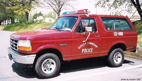 1986 Ford Bronco - This red police SUV has 'RIDLEY TOWNSHIP POLICE' text on its side and a phone number on the rear.