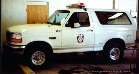 1986 Ford Bronco - This police SUV, likely a Ford Bronco from the early 1990s, is parked indoors with its emergency lights visible.