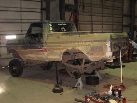 1977 Ford F-150 - A 1977 Ford F-150 truck is undergoing maintenance, with its rear end elevated on jack stands inside a workshop.