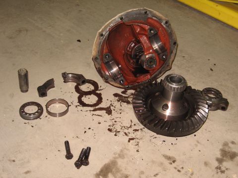 1977 Ford F-150 - Differential components, including gears and housing, are laid out on a concrete surface, suggesting a repair or rebuild.