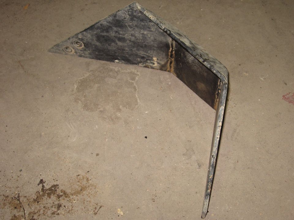 Bent black metal part with two circular indentations on the left