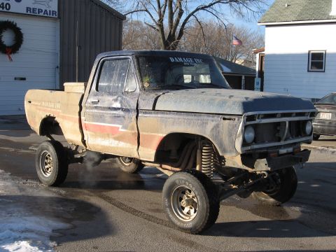 1977 Ford F-150 - This lifted 1977 Ford F-150 pickup truck is parked outside a repair shop on a cold day.