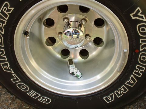 1989 Ford Bronco - Toy truck and trailer placed inside the rim of a vehicle wheel.