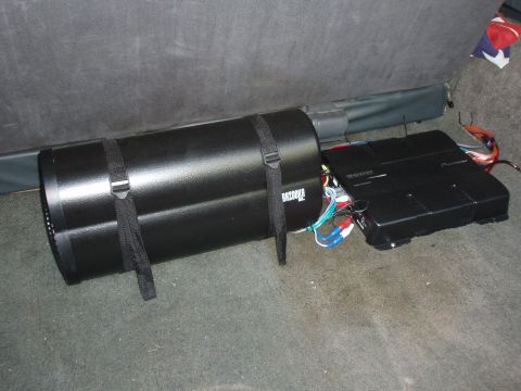 1989 Ford Bronco - Car audio system components, including a subwoofer and amplifier, are secured in the back of a vehicle.