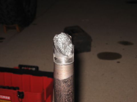 1977 Ford F-150 - Close-up of a damaged metal shaft, likely a vehicle part, with a red toolbox visible.