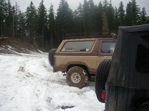1994 Ford Explorer - Two off-road vehicles are parked on a snowy trail surrounded by pine trees.