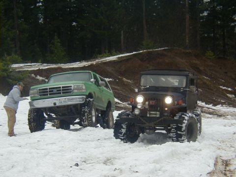 1994 Ford Explorer - A green 1994 Ford Bronco is parked in the snow next to a person, with a black Jeep also in the snowy scene.