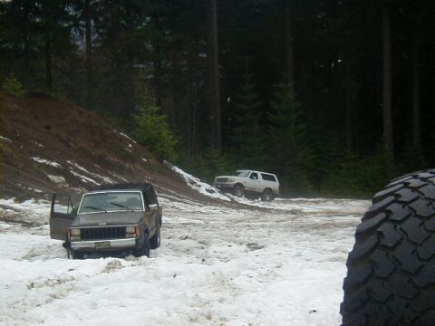 1994 Ford Explorer - A brown Jeep Cherokee sits in the snow with its door open, while another SUV drives in the background.