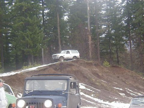 1994 Ford Explorer - Two off-road vehicles navigate a muddy, snow-dusted hill in a wooded area.