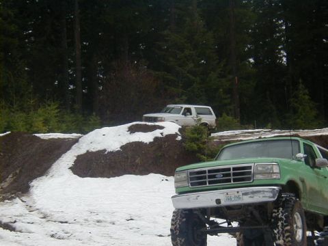 1994 Ford Explorer - Two off-road vehicles are parked in a snowy, wooded area with a dirt mound in the middle.