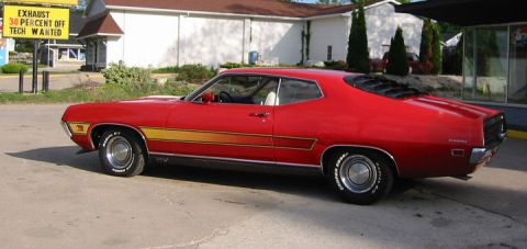 1972 Ford Ranchero - A red 1972 Ford Ranchero with distinctive yellow side stripes is viewed from a three-quarter front angle.