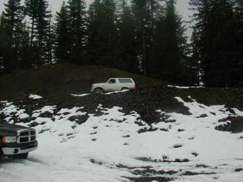 1994 Ford Explorer - A white SUV navigates a snowy, rocky terrain with a dark truck in the foreground.