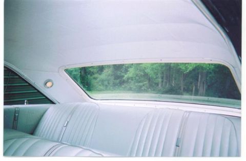 1972 Ford Ranchero - Interior view of a car's rear bench seat and headliner, with trees visible through the back window.