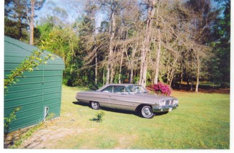 1972 Ford Ranchero - A silver 1964 coupe sits on a grassy lawn next to a green shed, with trees in the background.