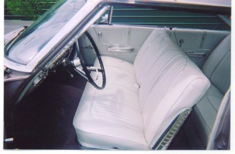 1972 Ford Ranchero - The interior of a classic car shows white bench seats and a large steering wheel.