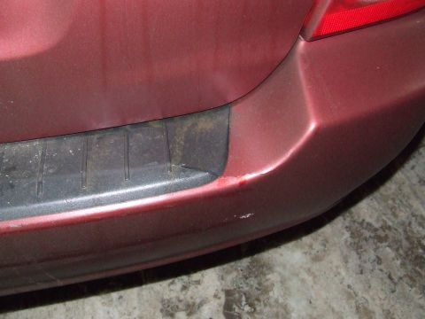 1990 Ford Bronco - Damage to the rear bumper of a red vehicle is visible, with scuffs on the black trim.