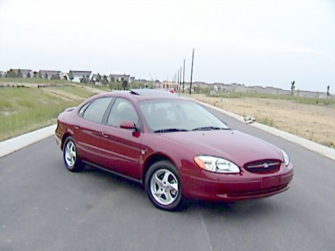 2002 Ford Taurus - This red 2002 Ford Taurus is parked on a road with a new housing development in the distance.