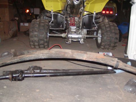 1991 Ford Bronco - A yellow ATV is parked in a garage with car parts laid out in front of it.